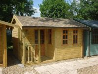 14 x 10 Artist Den featuring a corner covered veranda, and georgian windows. Felt tiles have been added to the building. 